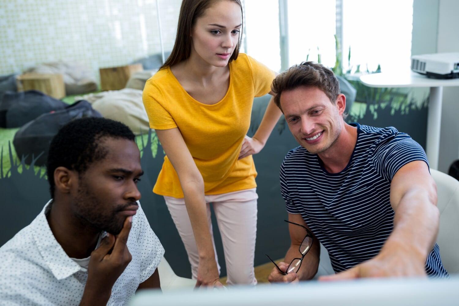 Equipe jovem analisando tela de computador em ambiente colaborativo