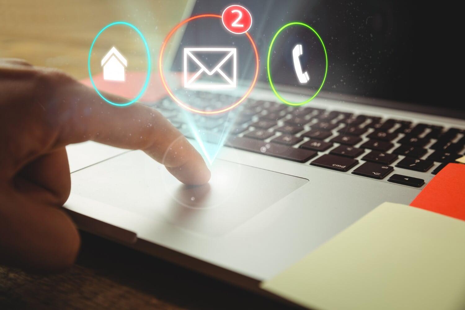 Dedo tocando touchpad de notebook com ícone de e-mail e notificações digitais